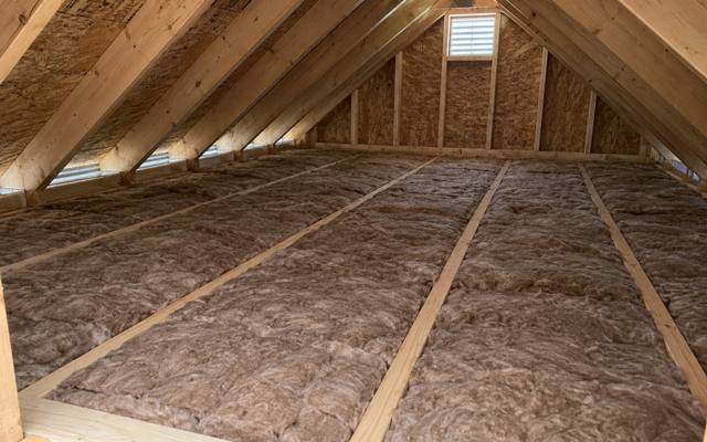 Brown batts in a tidy attic with a square gable vent letting light in at the far end